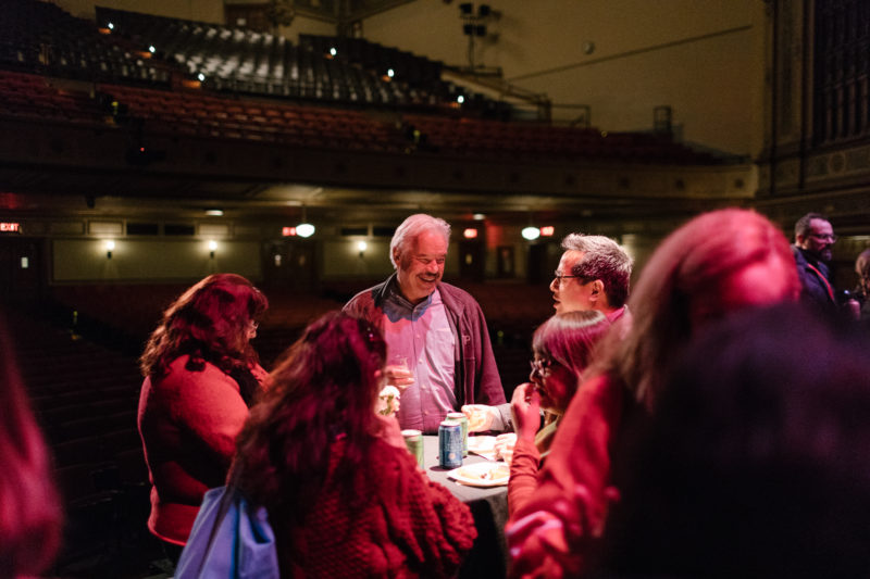 People laughing and having drinks on stage