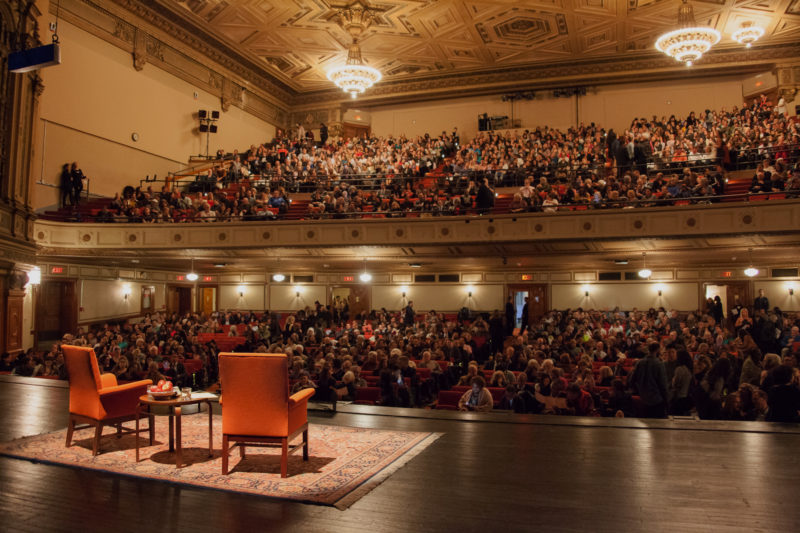 View from the stage of the City Arts "set" (two chairs and a Persian rug) with audiences flowing in to seating
