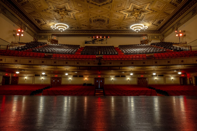 A full view of the house from up stage: the orchestra, loge and balcony seating, as well as the ornate ceiling with oversized chandeliers